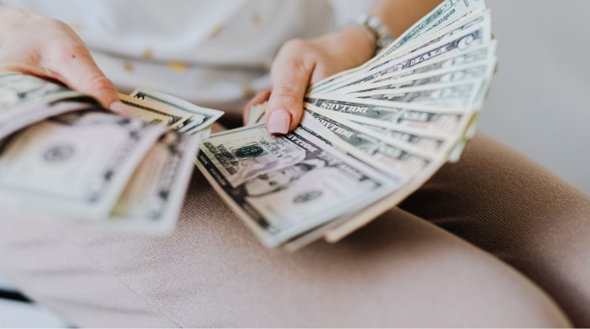A close up of someone's hands holding lots of paper bills.