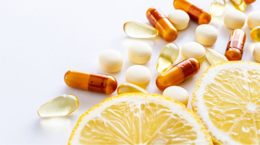 White and yellow vitamins on a white table with slices of lemons.