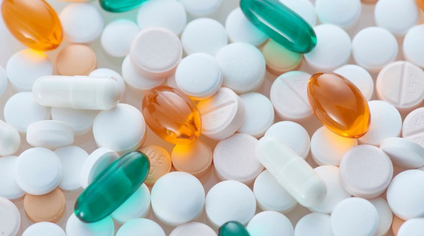 White, green, and yellow pills in a pile together.