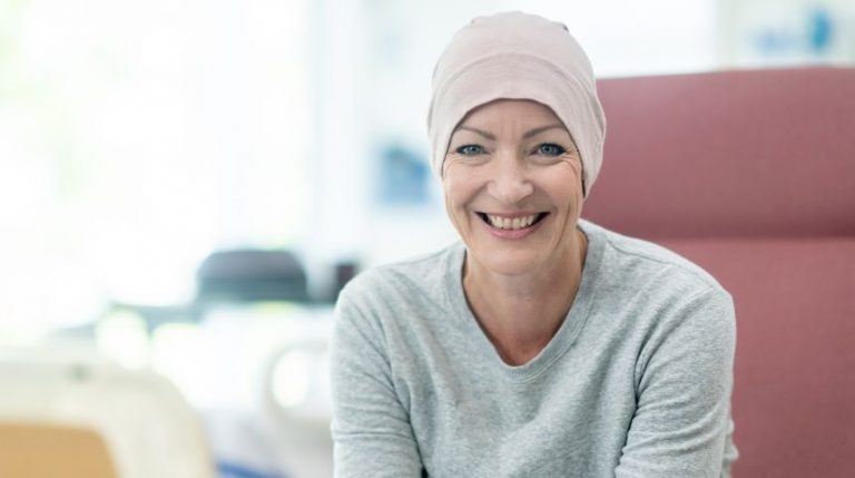 A cancer patient sitting in a chair, smiling.
