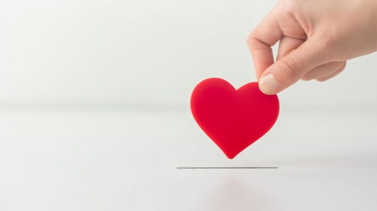 A hand holding a red heart