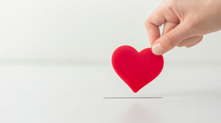 A hand holding a red heart