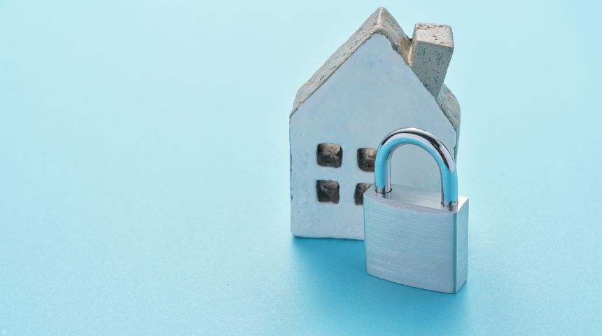 A small wooden model of a house with a metal lock.