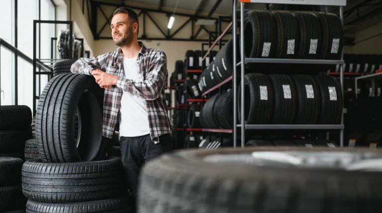 A man standing in a room full of different car tires.