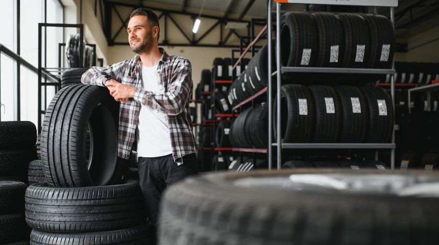 A man standing in a room full of different car tires.