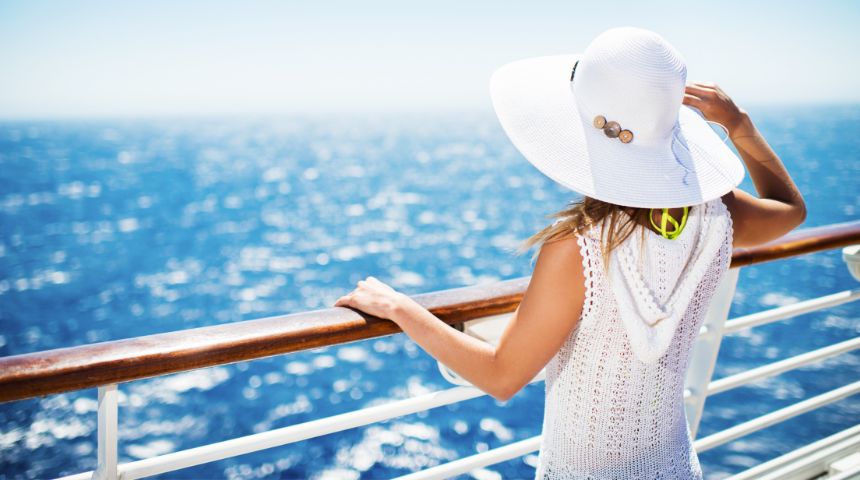A woman standing on a cruise ship, looking out at the water.